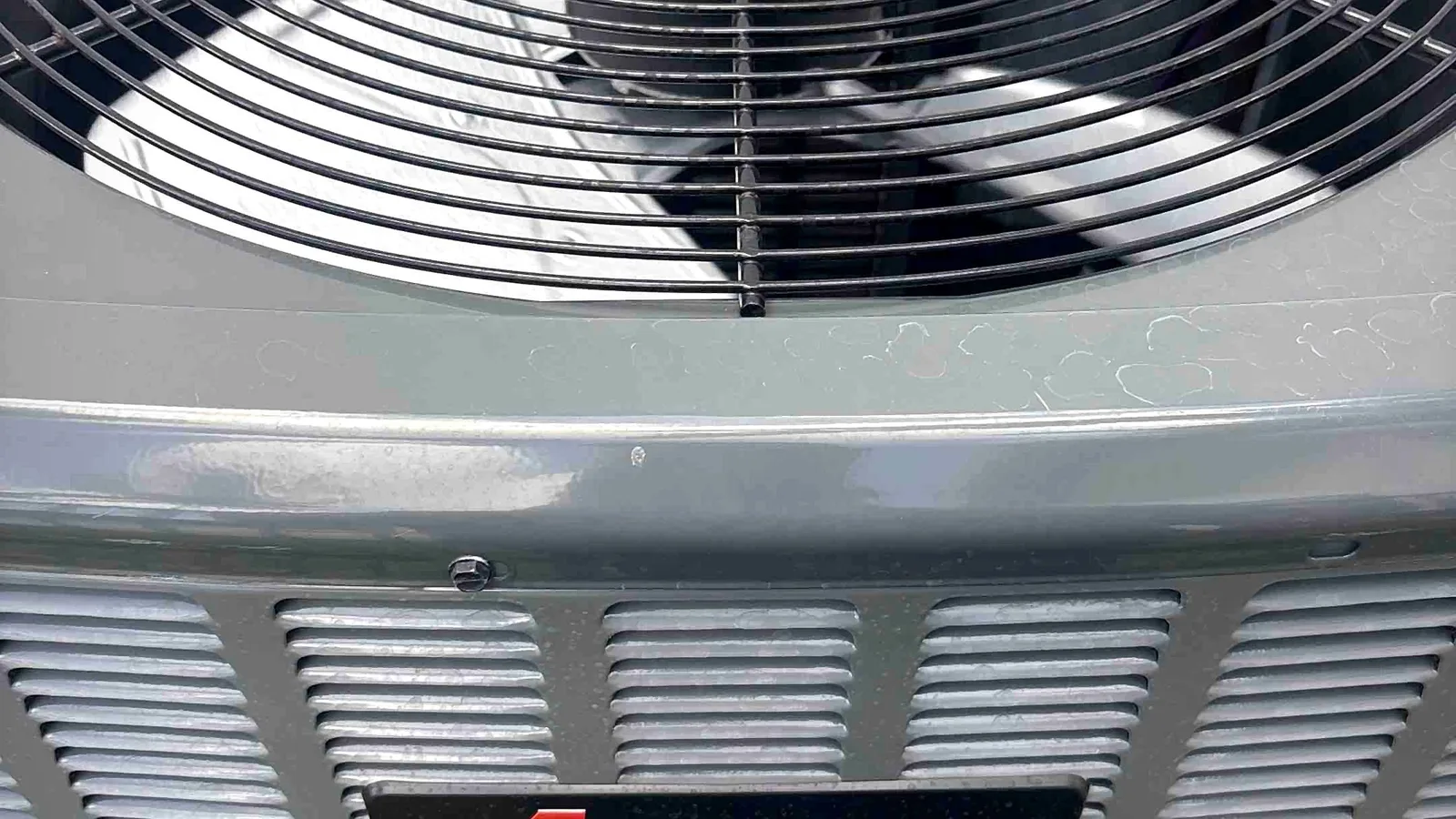 Close-up of an Amana condensing unit fan grille and brand badge on a clean installation
