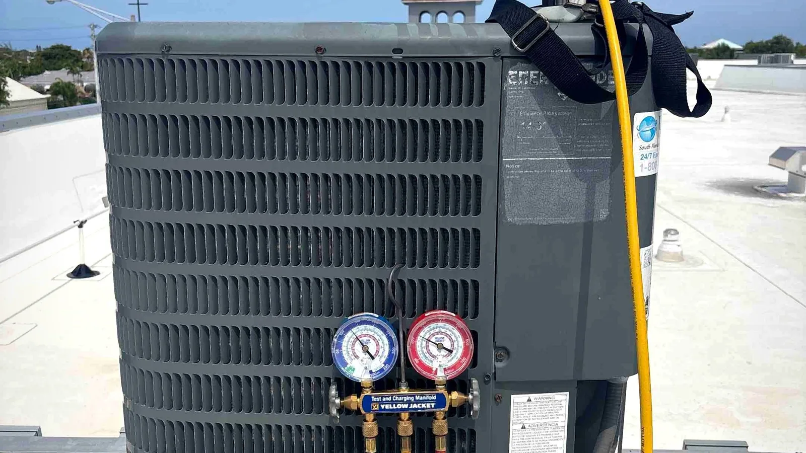 Technician charging a rooftop condenser with R-410A refrigerant using manifold gauges