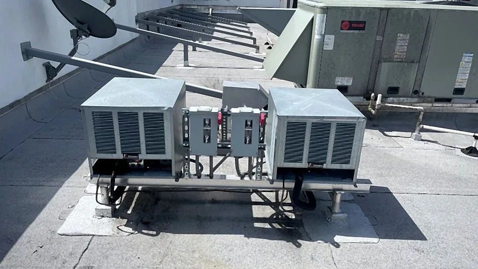 Commercial rooftop condensing units on a steel stand with electrical disconnects and refrigerant piping