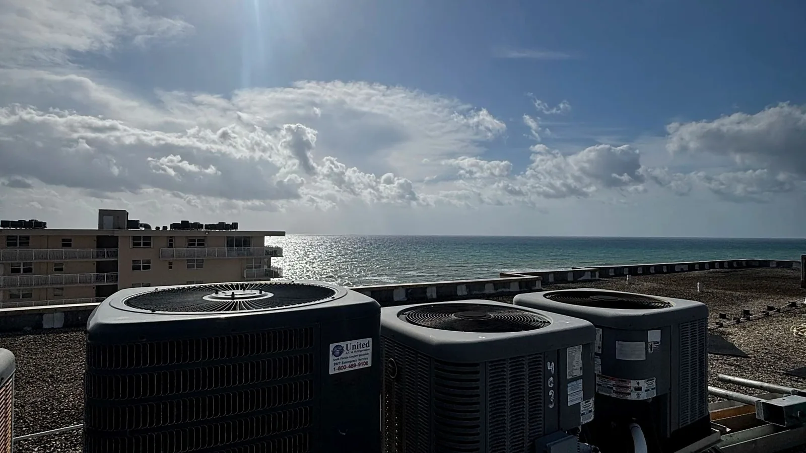 Rooftop air conditioning condensers on steel stands overlooking the ocean