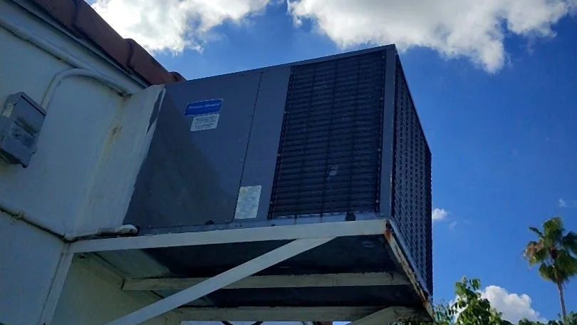 Packaged air conditioner mounted on a steel platform above a tile roof