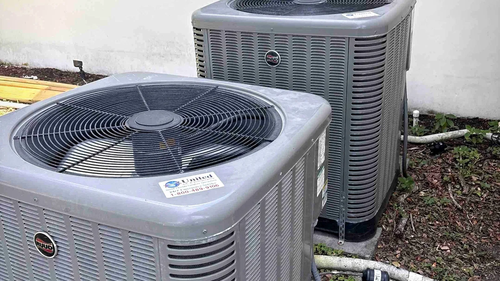 Pair of condensing units installed side by side on pads at a home exterior