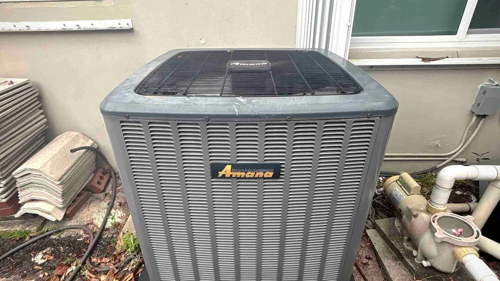 Amana condenser on a composite equipment pad at the side of a residential property