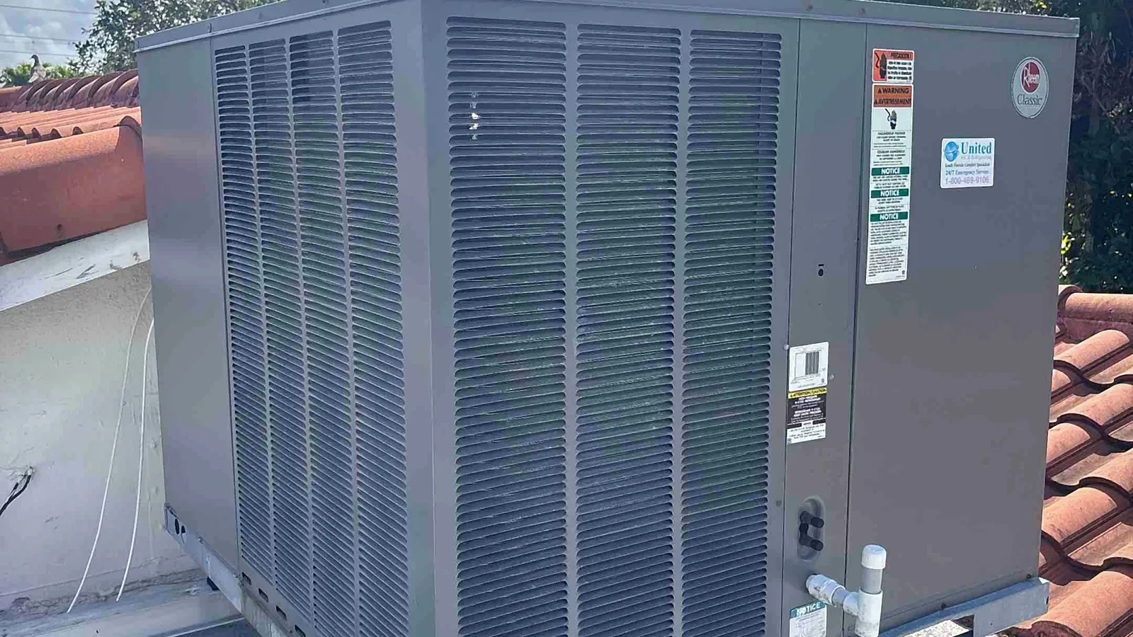 Packaged rooftop HVAC unit mounted on a steel frame above a tile roof