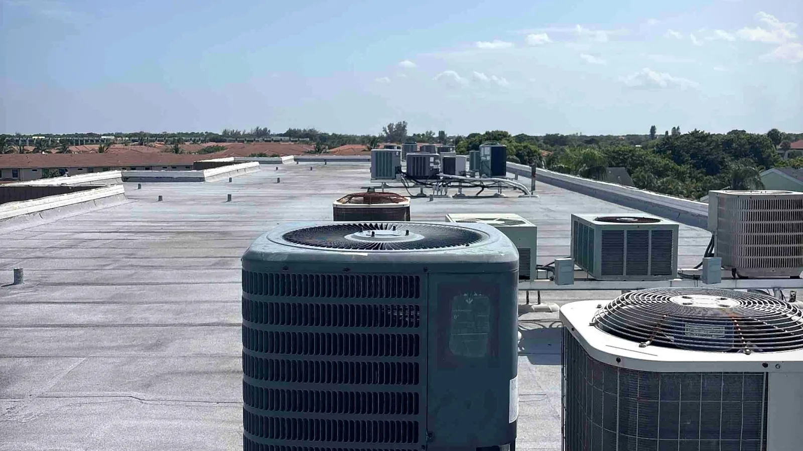 Rooftop commercial air conditioning condensers on steel racks with refrigerant line supports