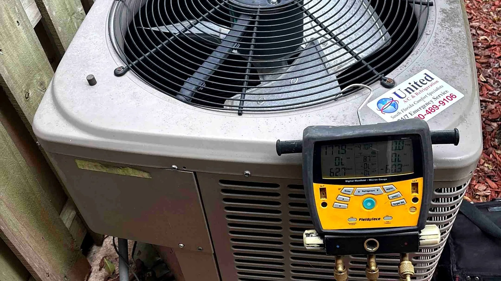 Digital manifold gauges connected to an outdoor condenser during a refrigerant charge check