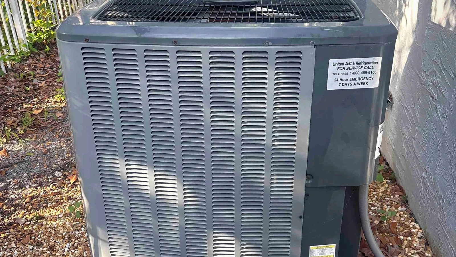 Outdoor condensing unit on a gravel side-yard pad with clean coil fins