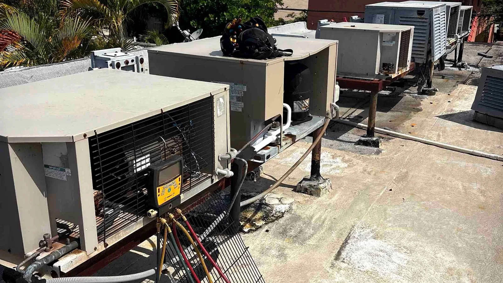 Commercial rooftop package units opened for service with digital manifold gauges attached