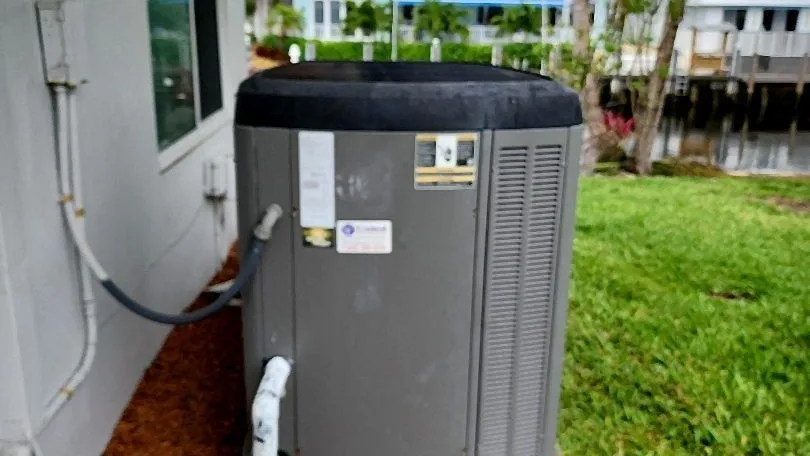 Residential condenser beside a waterfront home with neatly routed refrigerant and drain lines