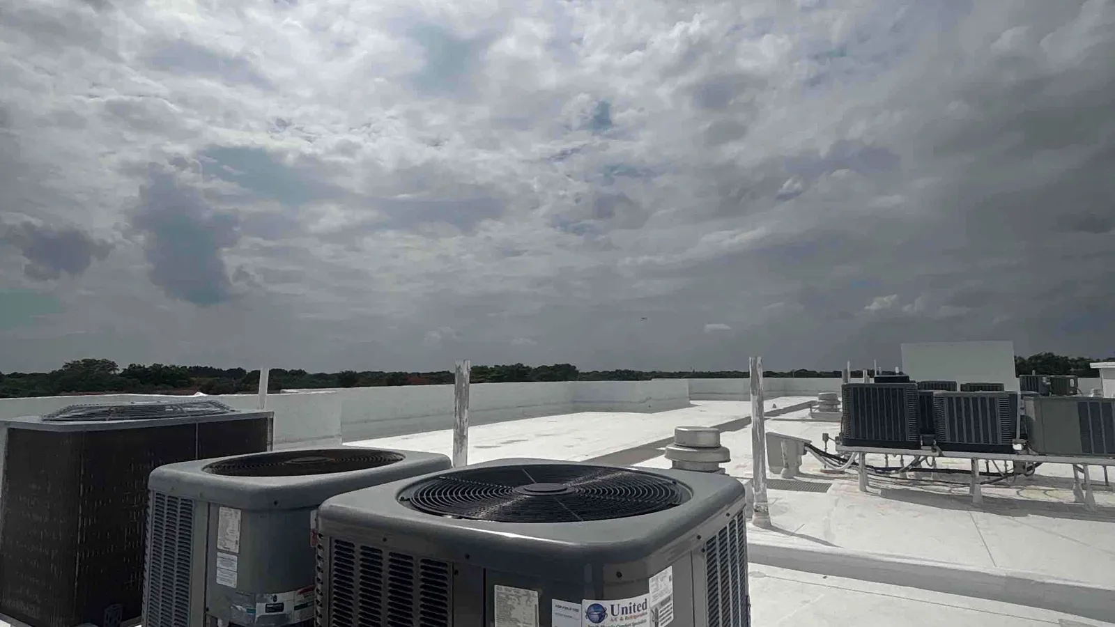 Rooftop air conditioning condensers under a heavy storm sky on a commercial building