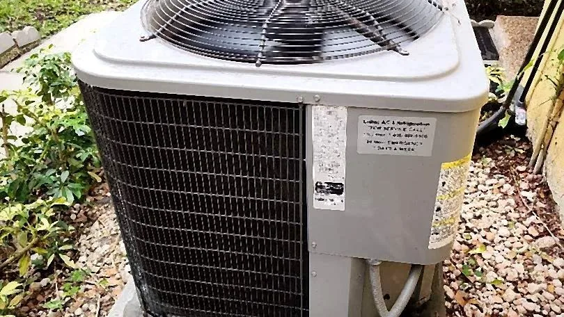Aging condenser with a dirty coil on a concrete pad, a candidate for cleaning or replacement