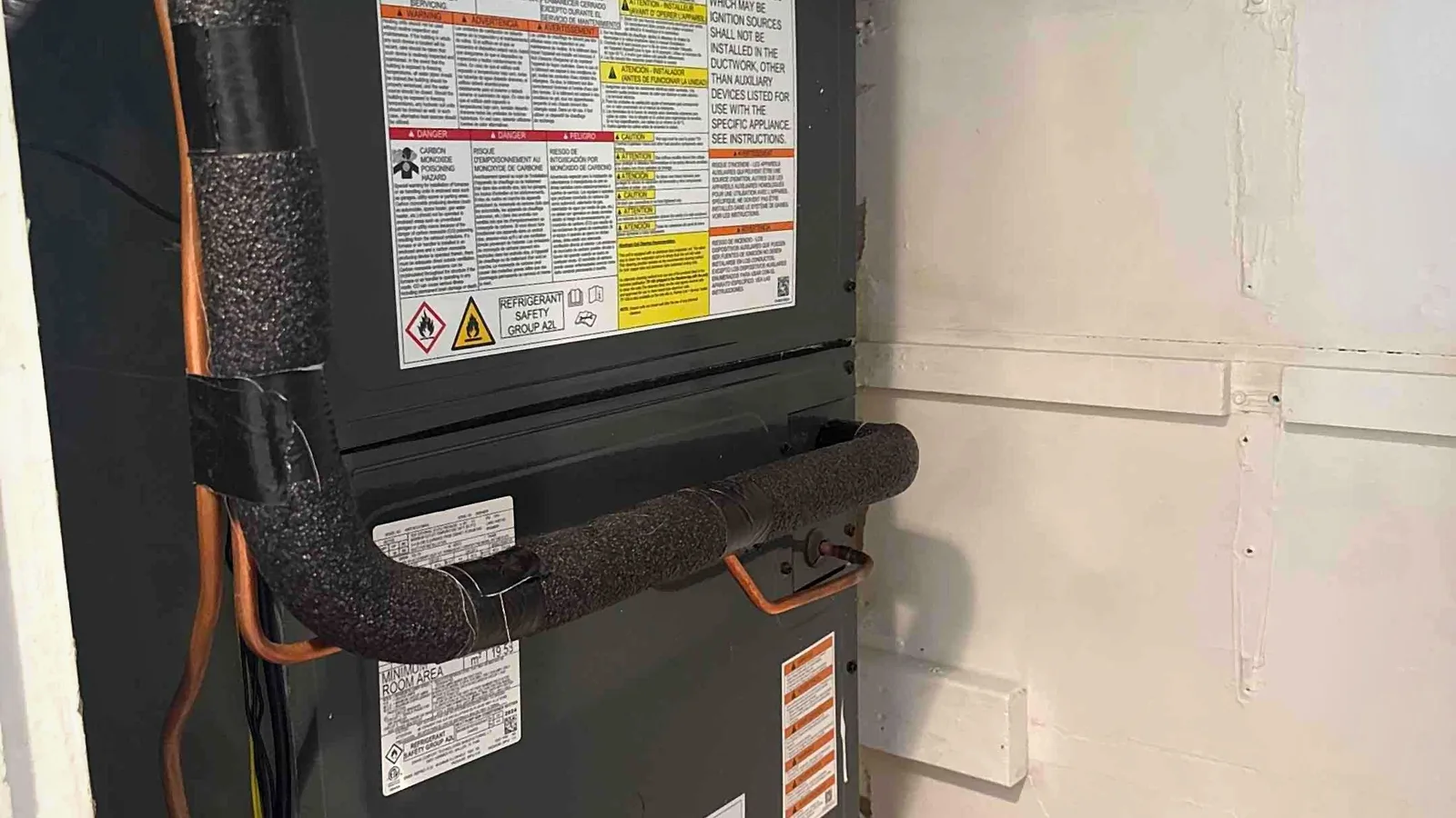 Vertical Amana air handler installed in a closet with insulated lines and condensate safety switch