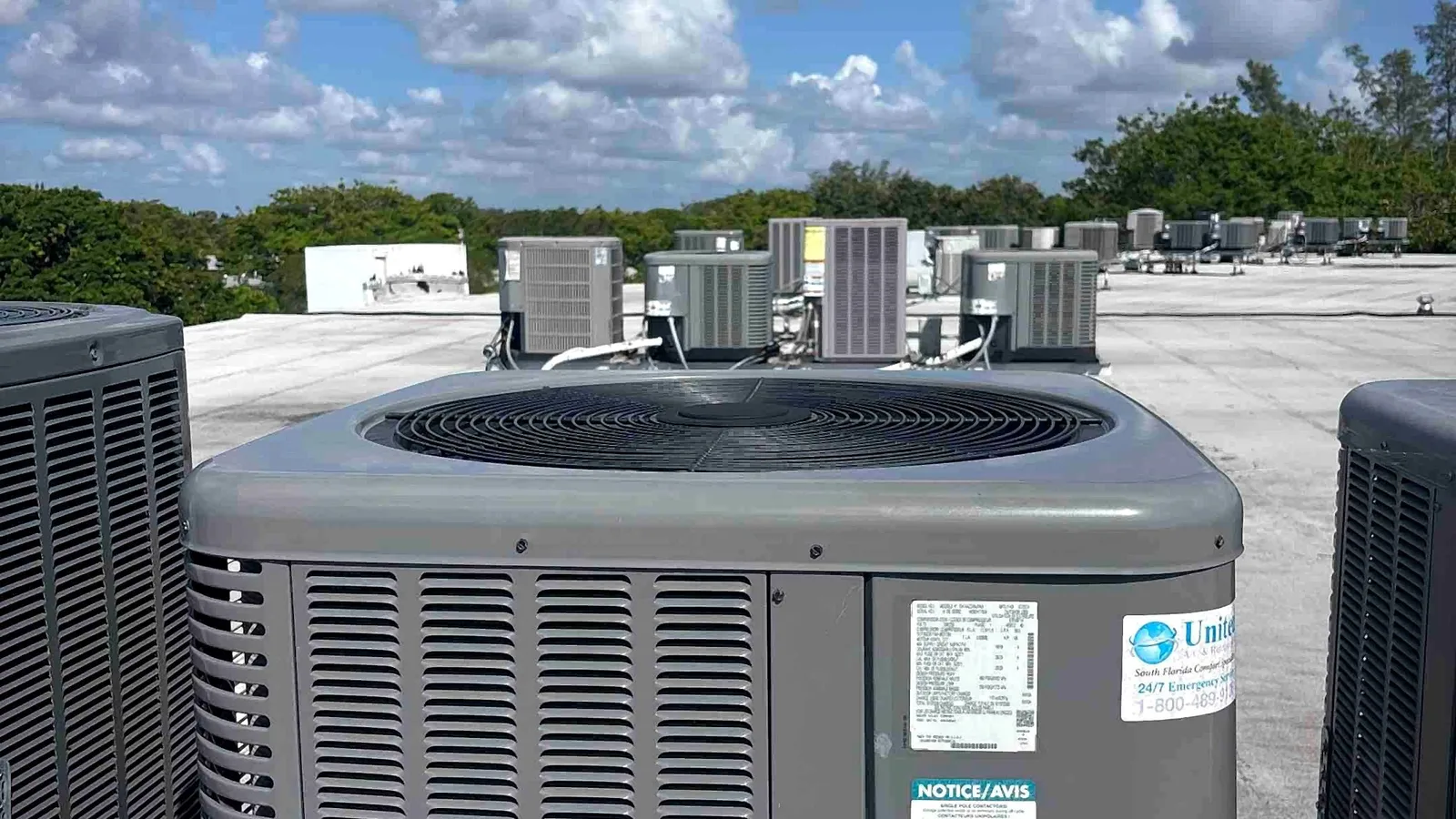 Rows of rooftop condensing units serving a large multi-unit commercial building