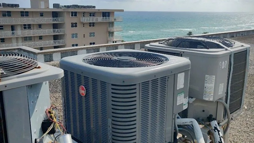Condensers on an oceanfront rooftop with refrigerant linesets and one unit opened for service