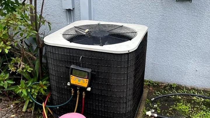 Manifold gauges and refrigerant recovery tank connected to a residential condenser during service