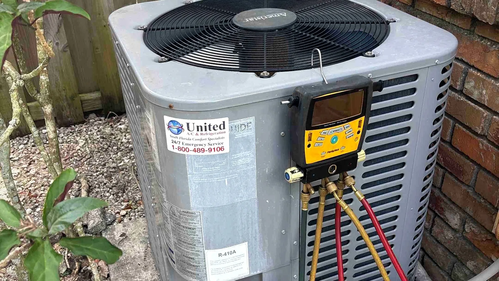 Digital manifold gauges connected to an Amana condenser during a refrigerant charge check