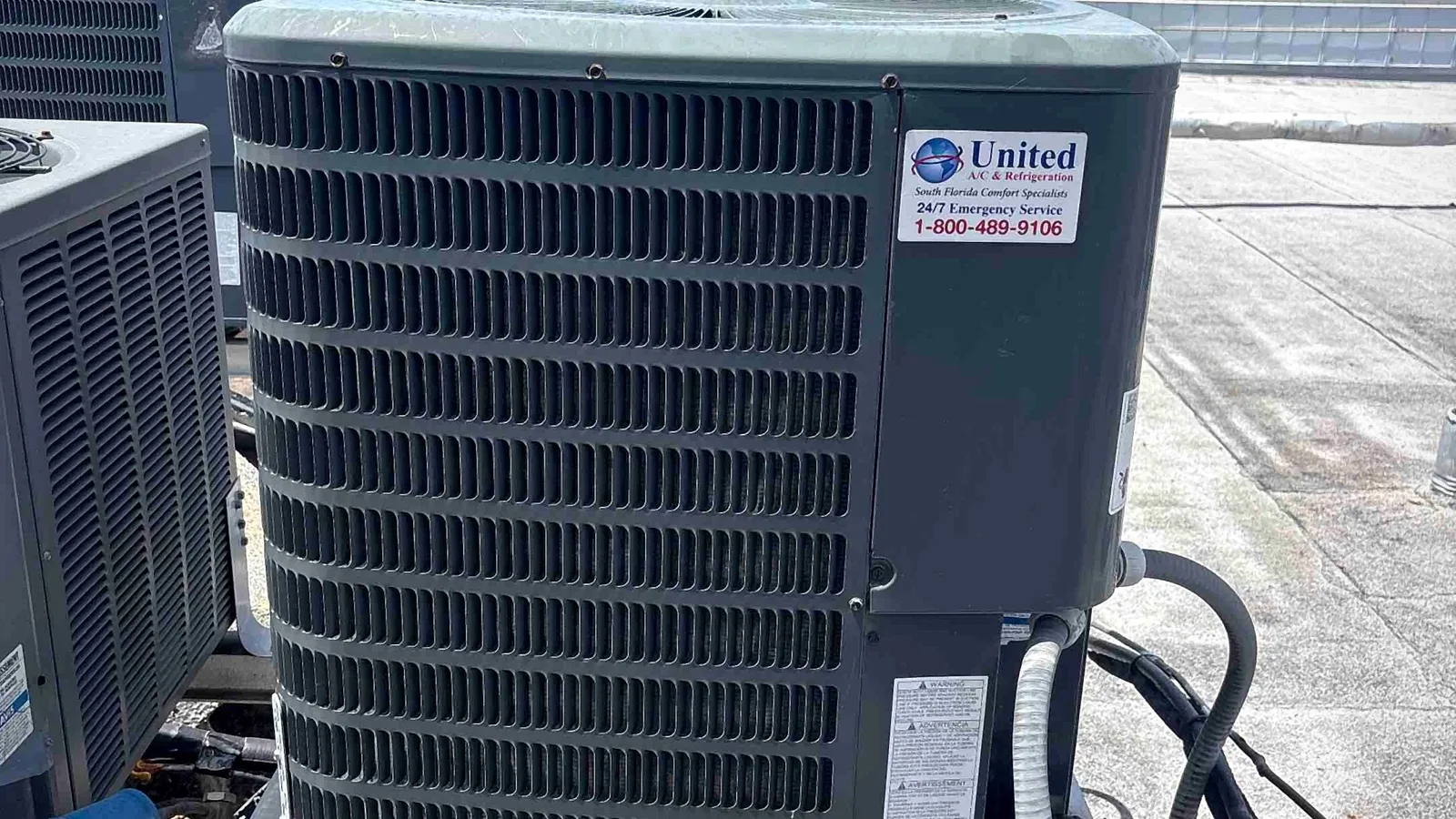 Neatly installed rooftop condenser on a raised stand with tidy electrical whip and disconnect