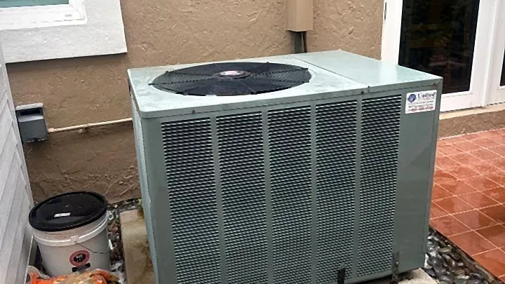 Horizontal packaged HVAC unit on a concrete pad beside a residential patio entrance