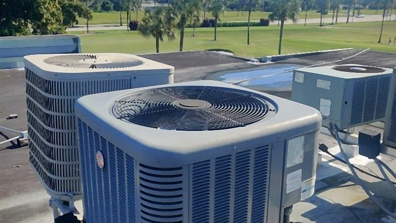 Rooftop condensers on steel rails overlooking a palm-lined golf course