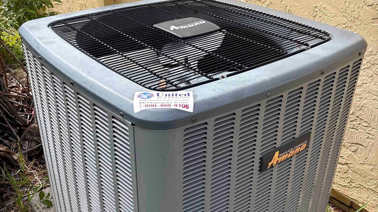Amana outdoor condensing unit installed on a concrete pad beside a stucco home