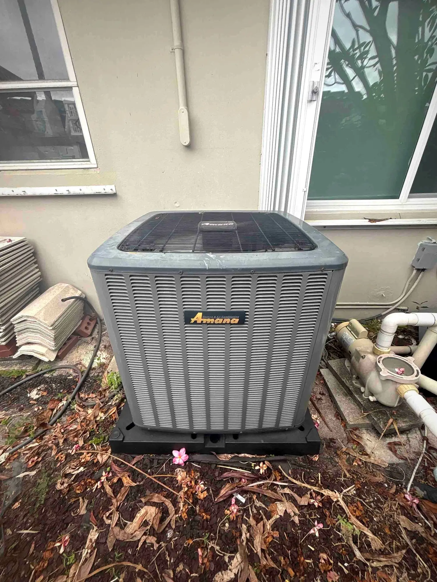 Amana condenser on a composite equipment pad at the side of a residential property
