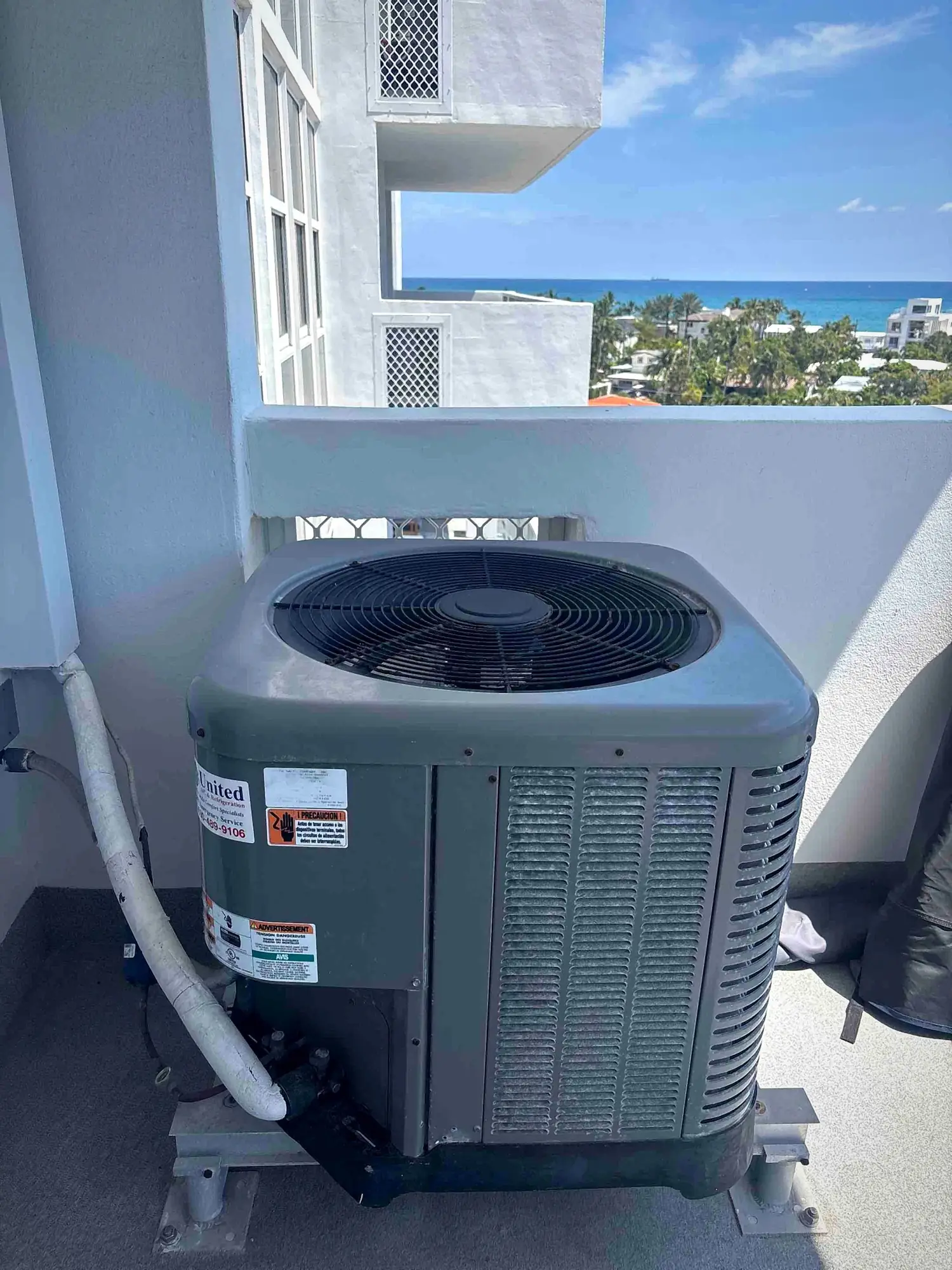 Balcony-mounted air conditioning condenser at a high-rise overlooking the ocean