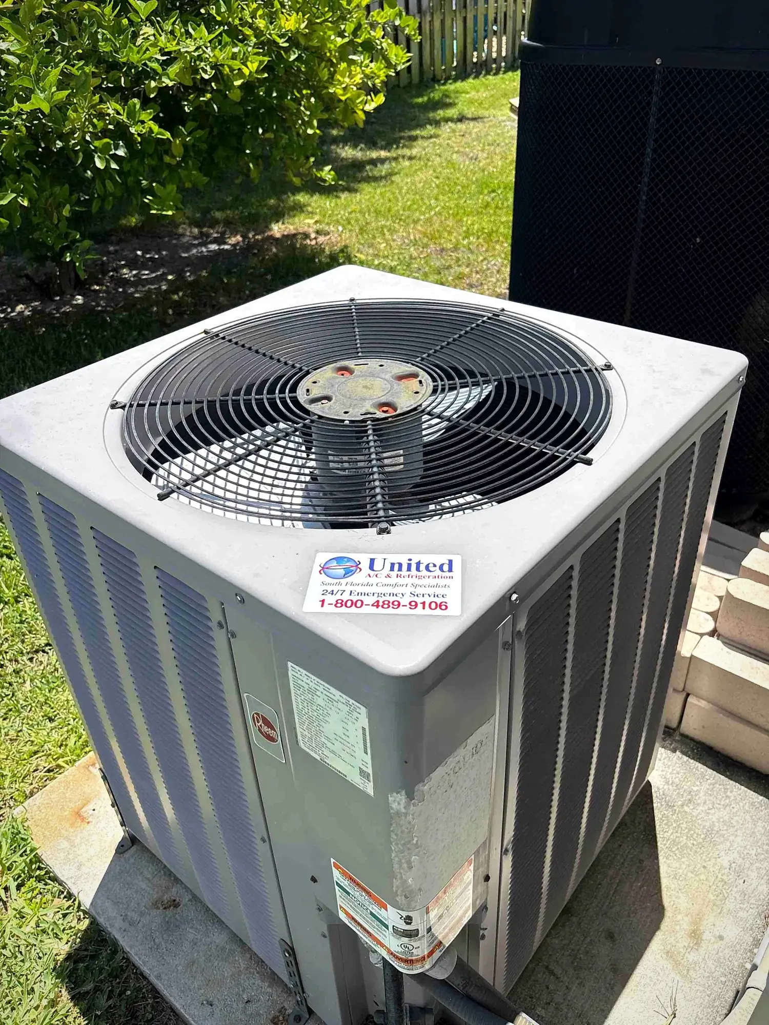 Outdoor condenser unit on a concrete pad in a sunny residential back yard