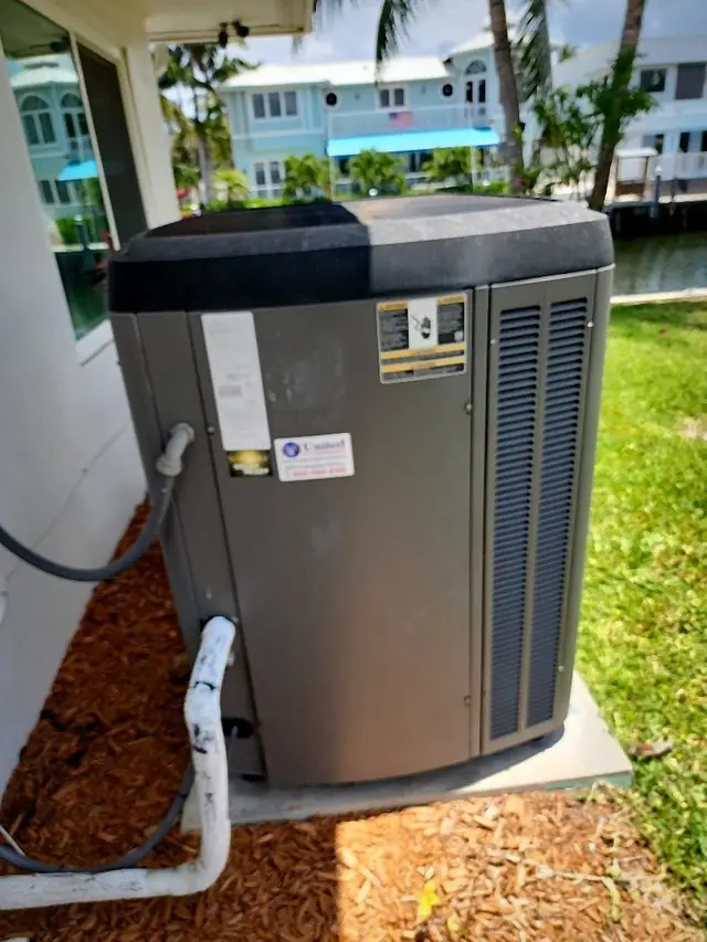 Residential condensing unit installed beside a canal-front home with insulated suction line