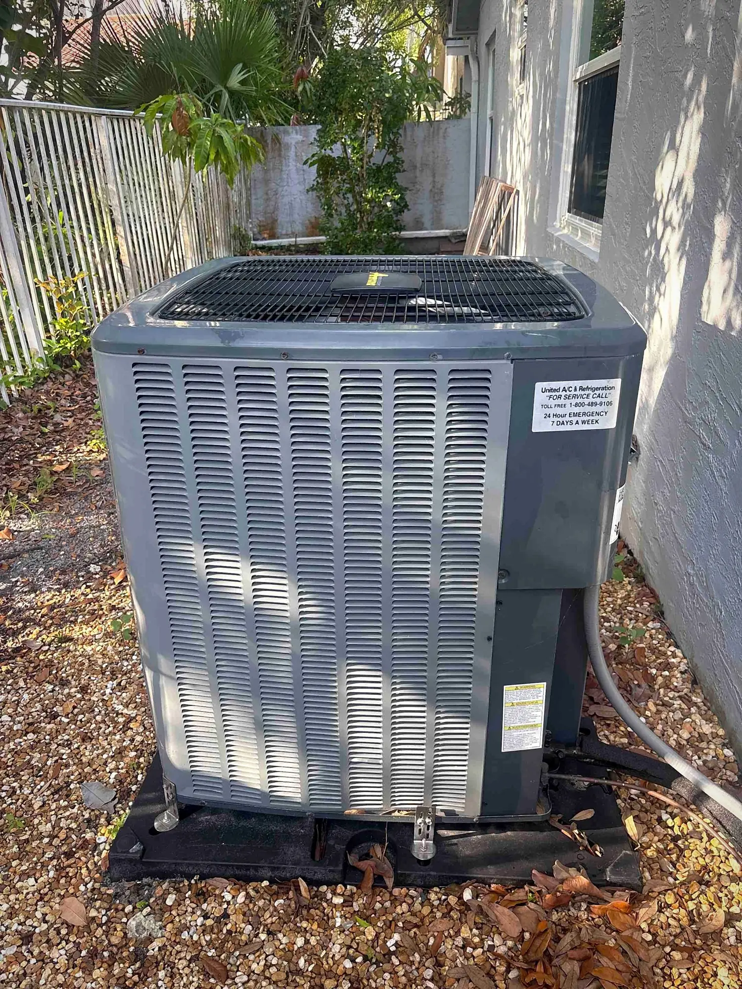 Outdoor condensing unit on a gravel side-yard pad with clean coil fins