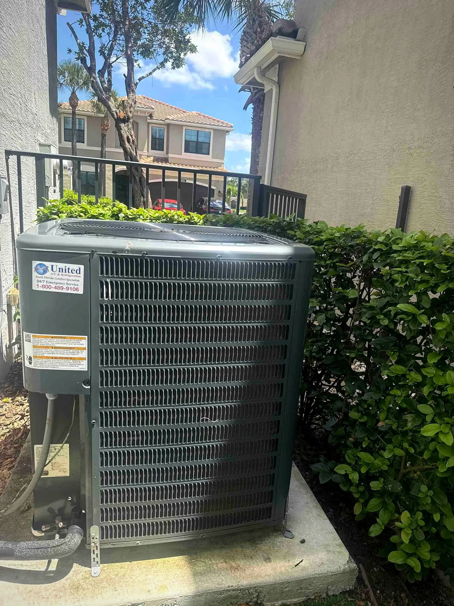 Outdoor condenser on a concrete pad beside a townhome in a tile-roof community