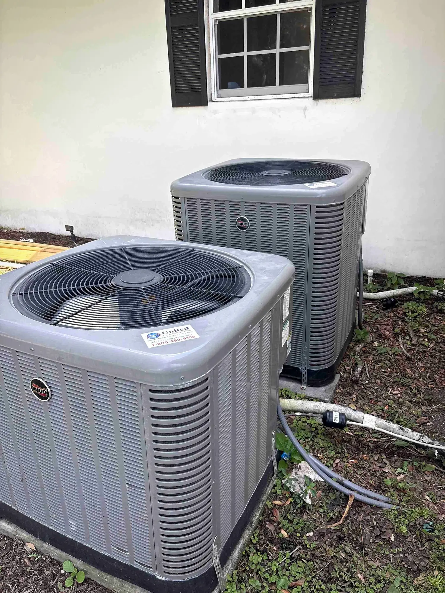 Pair of condensing units installed side by side on pads at a home exterior