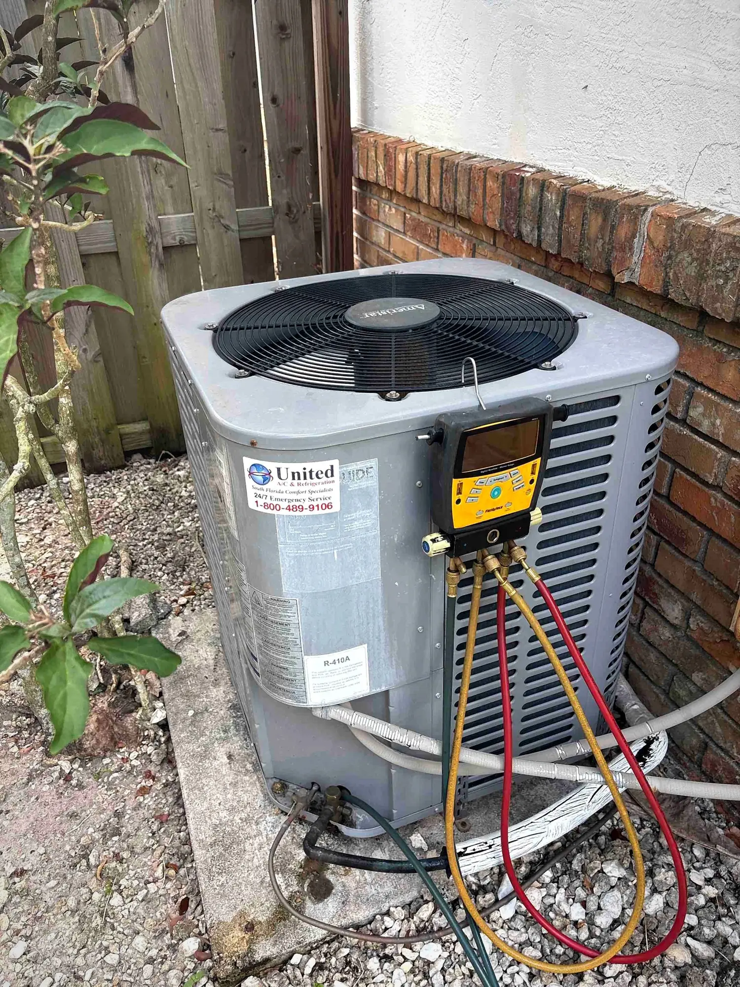Digital manifold gauges connected to an Amana condenser during a refrigerant charge check