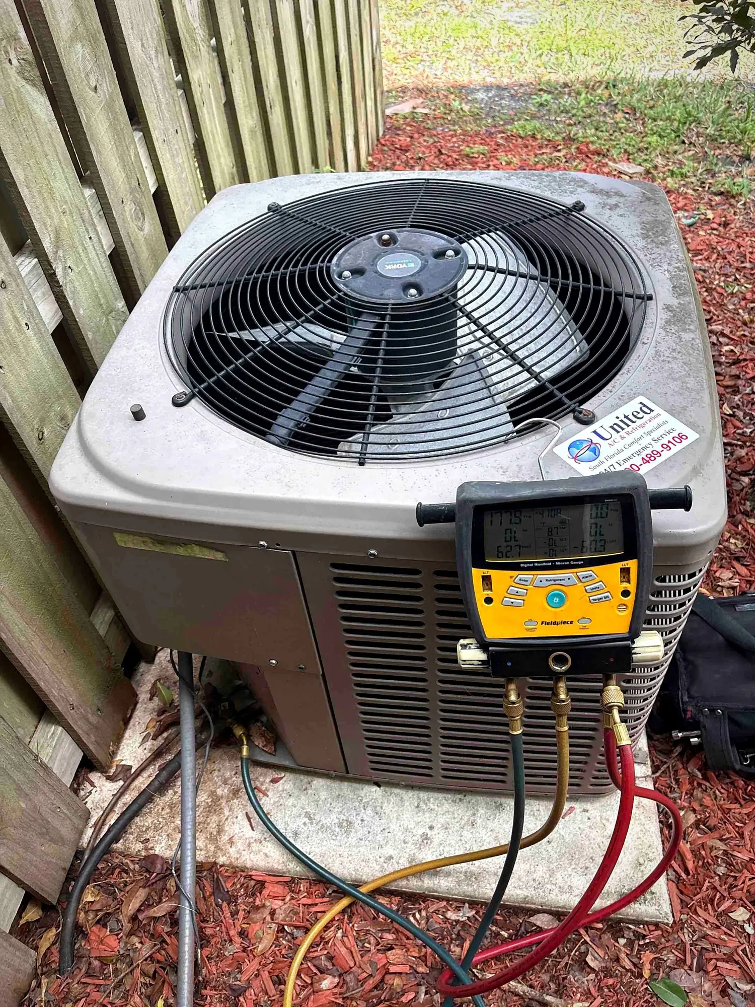 Digital manifold gauges connected to an outdoor condenser during a refrigerant charge check