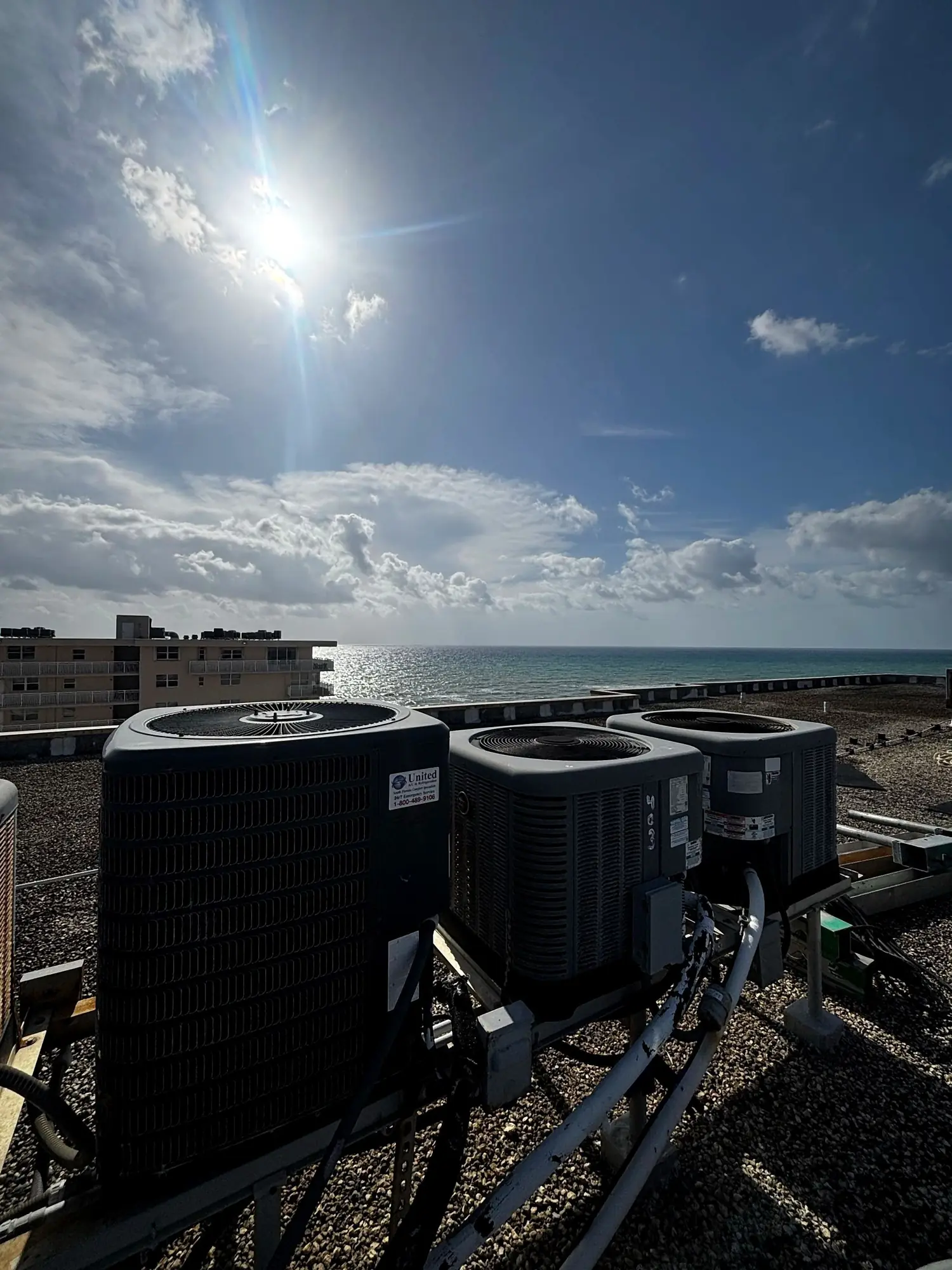 Rooftop air conditioning condensers on steel stands overlooking the ocean