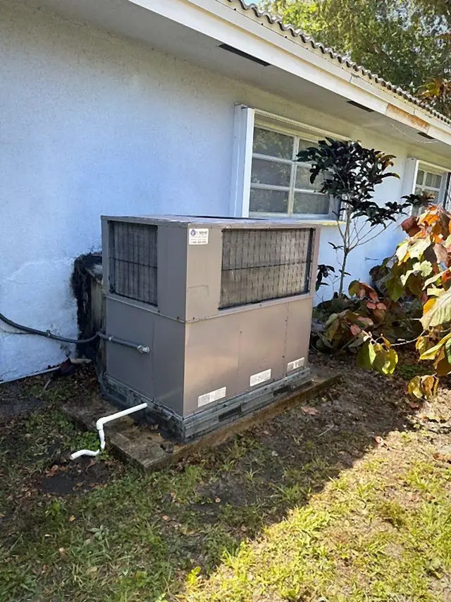 Ground-mounted packaged air conditioning unit on a slab with condensate drain line