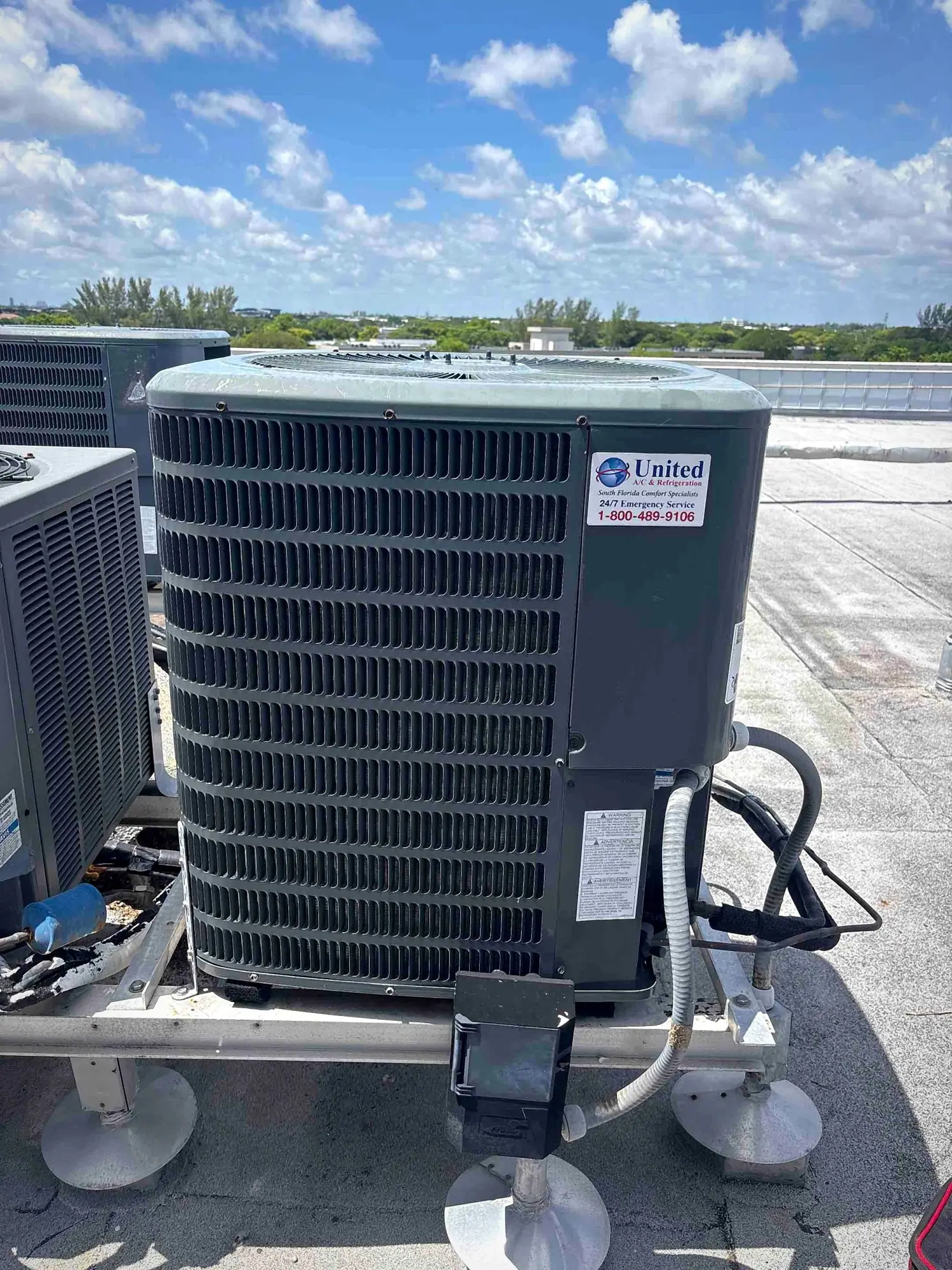 Neatly installed rooftop condenser on a raised stand with tidy electrical whip and disconnect