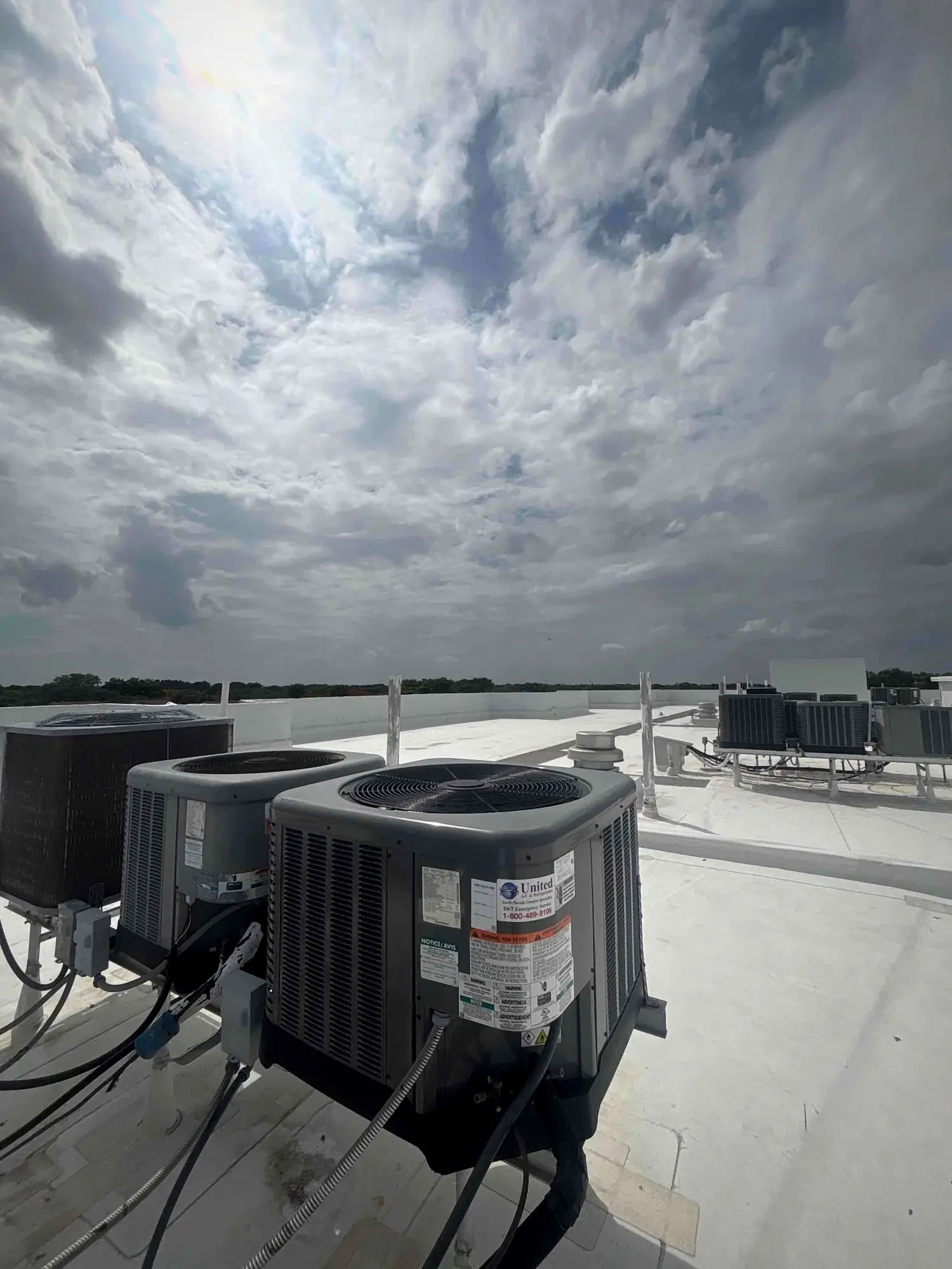 Rooftop air conditioning condensers under a heavy storm sky on a commercial building