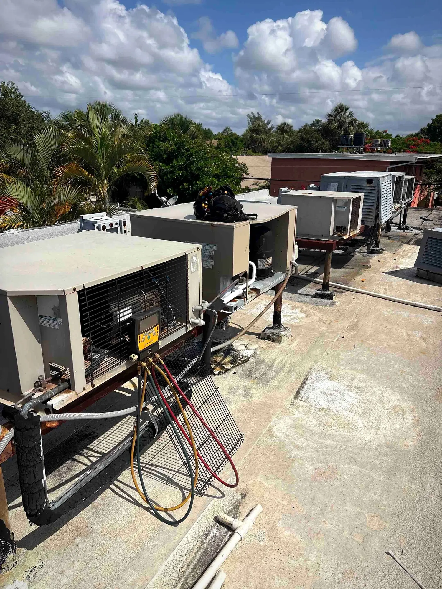 Commercial rooftop package units opened for service with digital manifold gauges attached