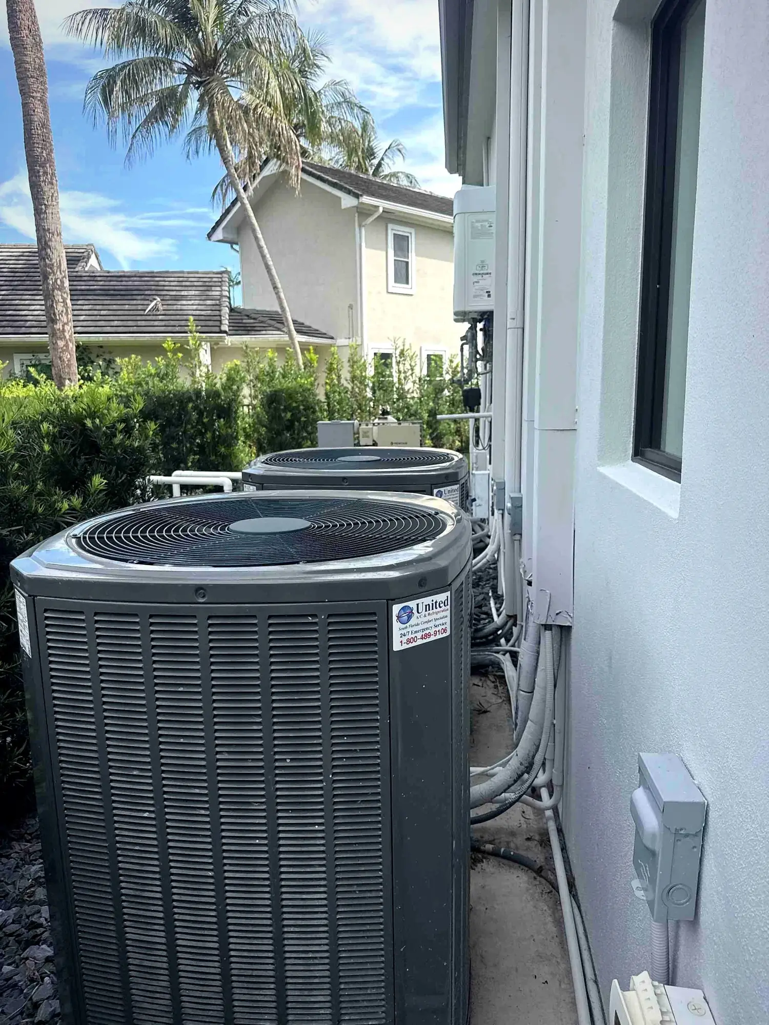 Pair of residential condensers with neatly insulated line sets alongside a stucco home